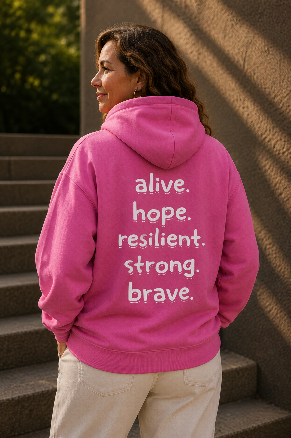 Person wearing a pink hoodie with motivational text on the back, standing on steps.